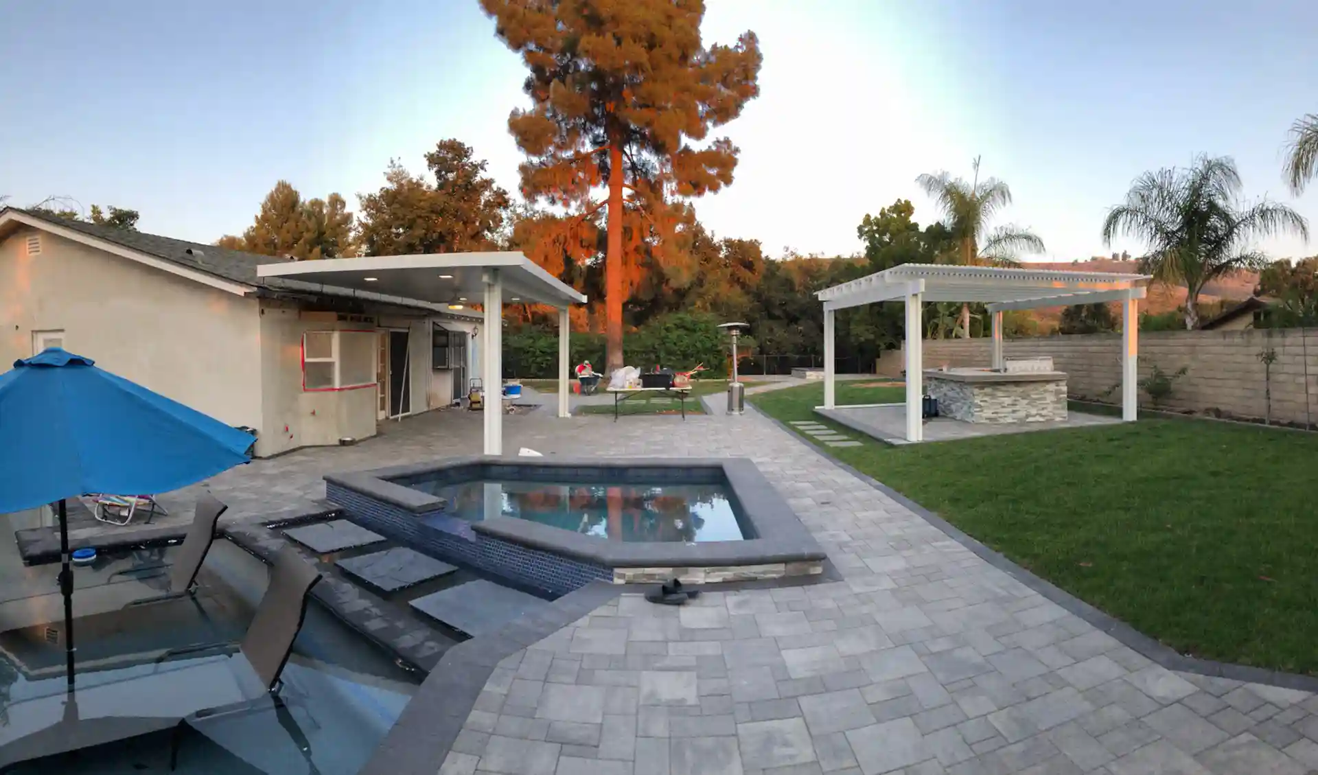 photo of a paver patio, paver patio outdoor kitchen with a pergola, and a paver patio pool deck