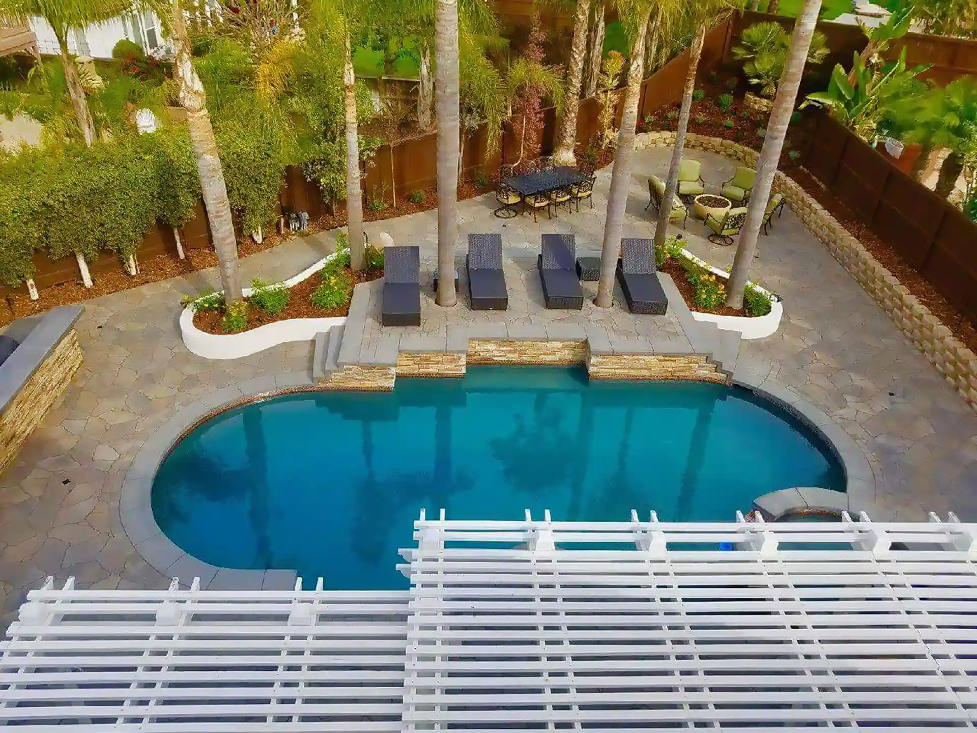 photo of a paver pool deck with a raised area with outdoor seating and pergolas 